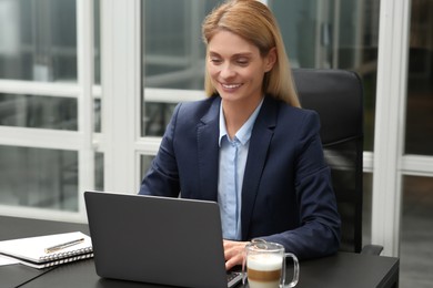 Woman working on laptop at black desk in office