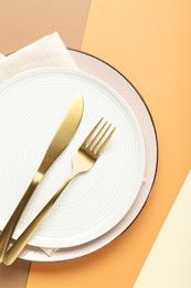 Ceramic plates, cutlery and napkin on color background, top view
