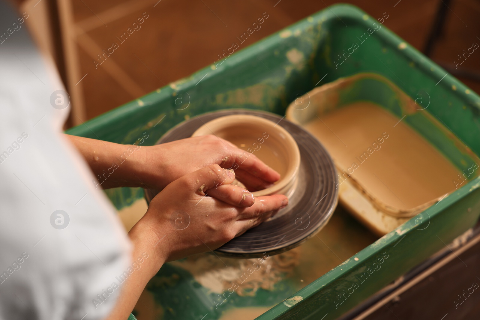 Photo of Clay crafting. Woman making bowl on potter's wheel, closeup