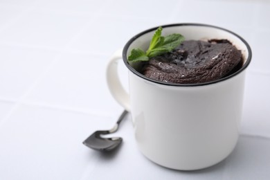 Tasty chocolate mug pie and spoon on white table, space for text. Microwave cake recipe