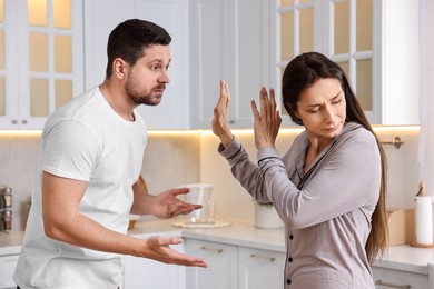 Photo of Tired wife stopping her husband in kitchen. Relationship problems