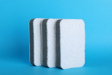 Photo of Three sponges on light blue background. Cleaning tool