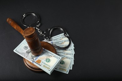 Photo of Law gavel, dollars and handcuffs on grey table, above view. Space for text