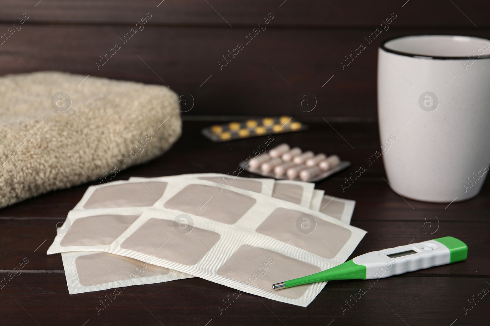 Photo of Mustard plasters, thermometer and pills on wooden table
