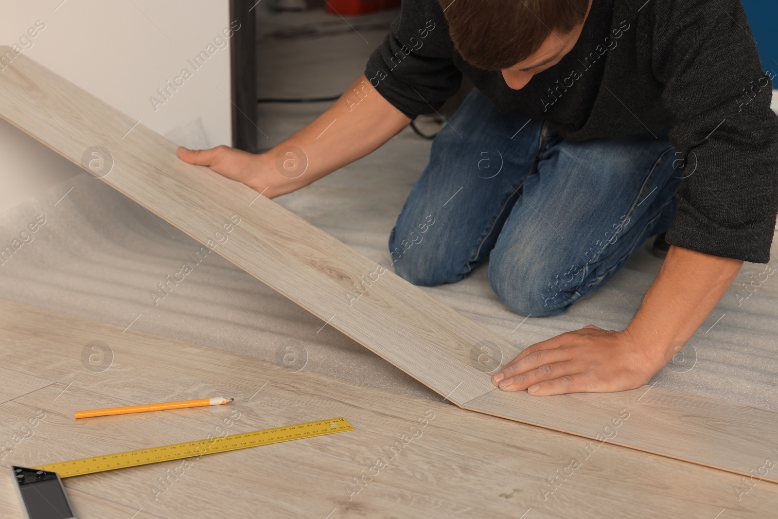 Photo of Professional worker installing new laminate flooring, closeup