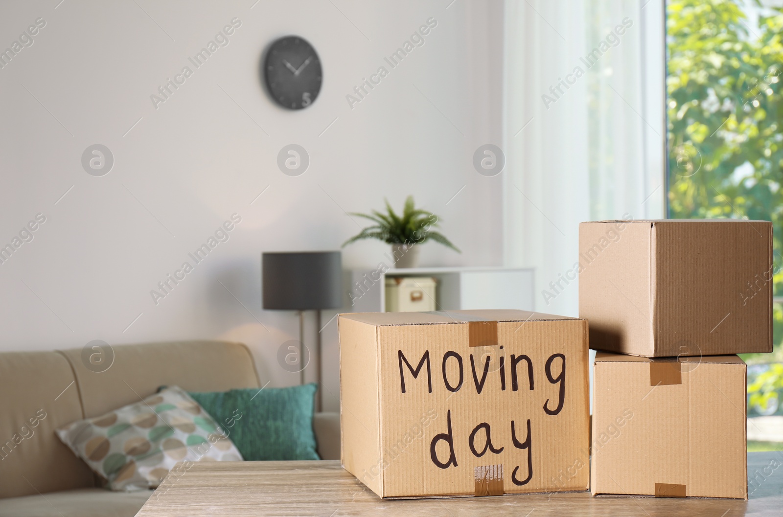 Photo of Cardboard boxes on table against blurred background. Moving day