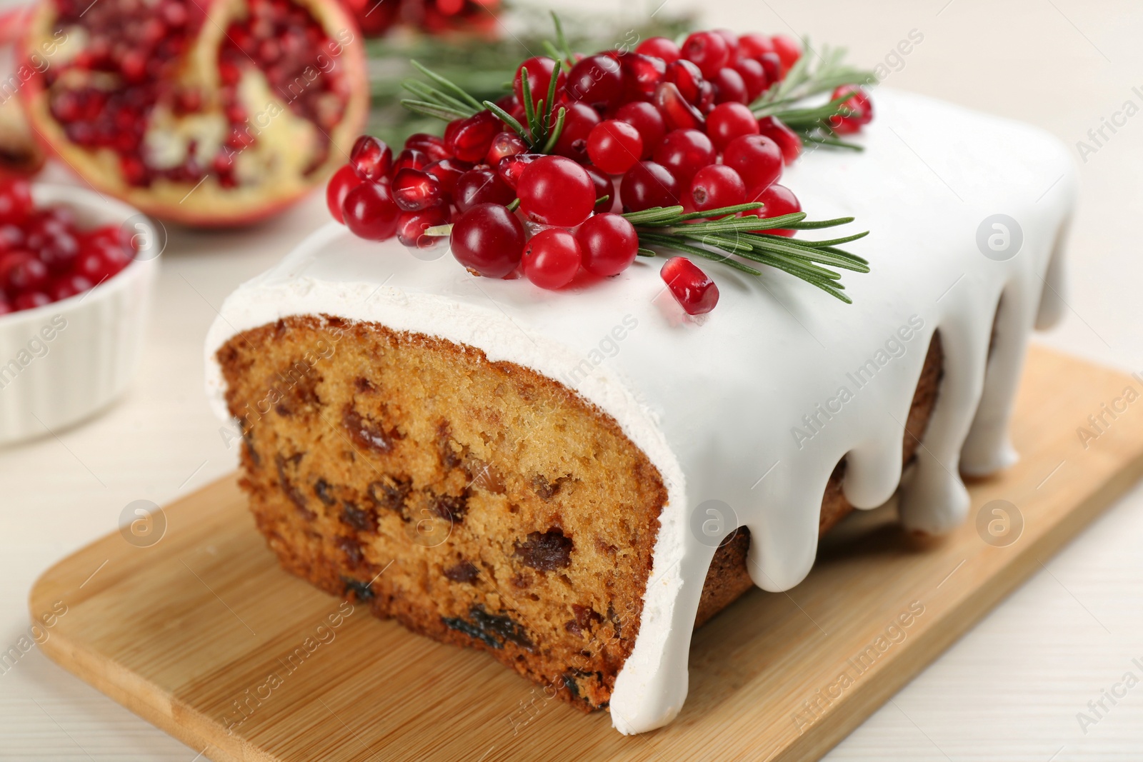 Photo of Traditional classic Christmas cake decorated with cranberries, pomegranate seeds and rosemary on white table, closeup