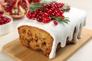 Traditional classic Christmas cake decorated with cranberries, pomegranate seeds and rosemary on white table, closeup