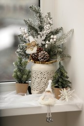 Photo of Beautiful window sill decorated for Christmas with fir trees, cones and artificial snow indoors