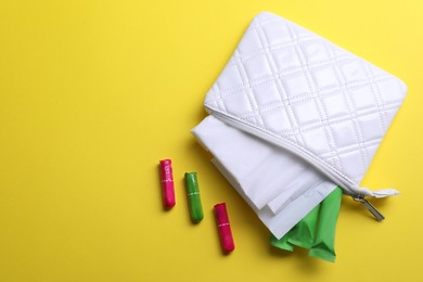 Photo of Bag with menstrual pads and tampons on yellow background, flat lay. Space for text
