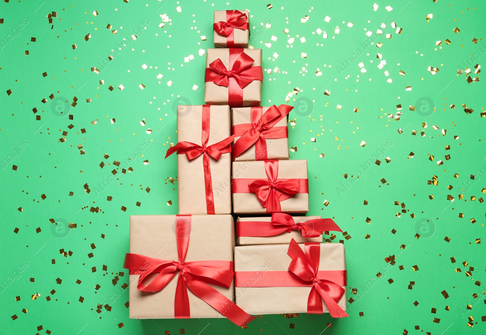 Photo of Christmas tree made with different gift boxes on green background, flat lay