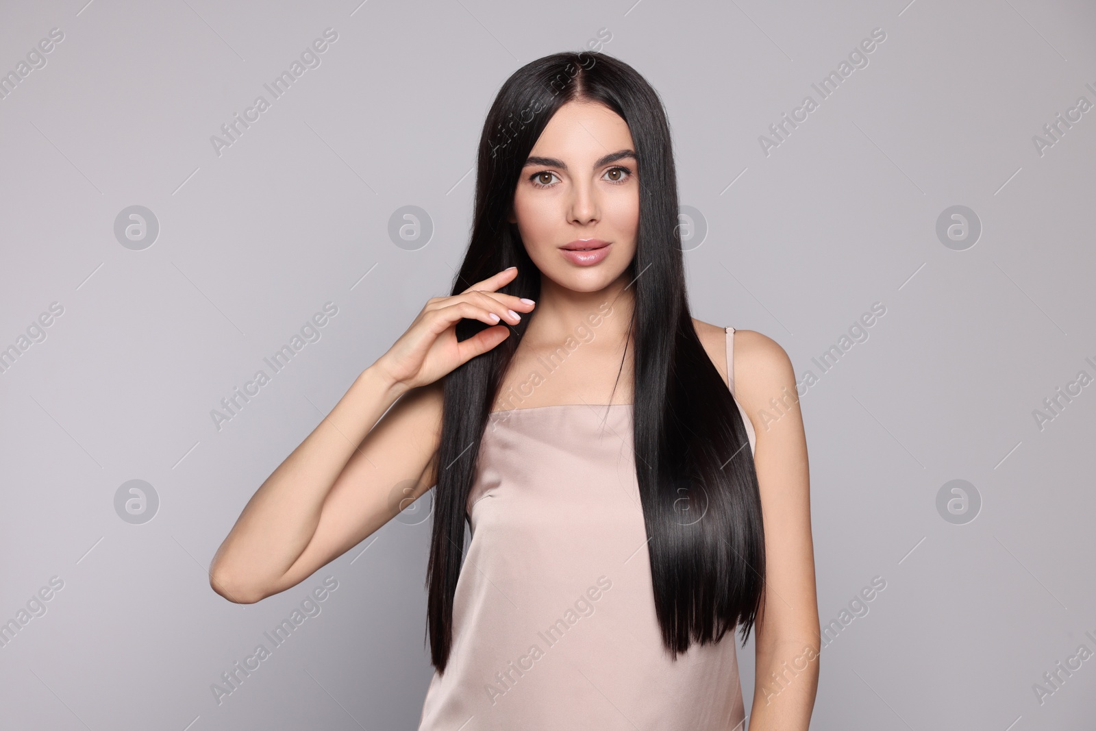 Photo of Portrait of beautiful young woman with healthy strong hair on light grey background