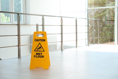 Photo of Safety sign with phrase Caution wet floor, indoors. Cleaning service