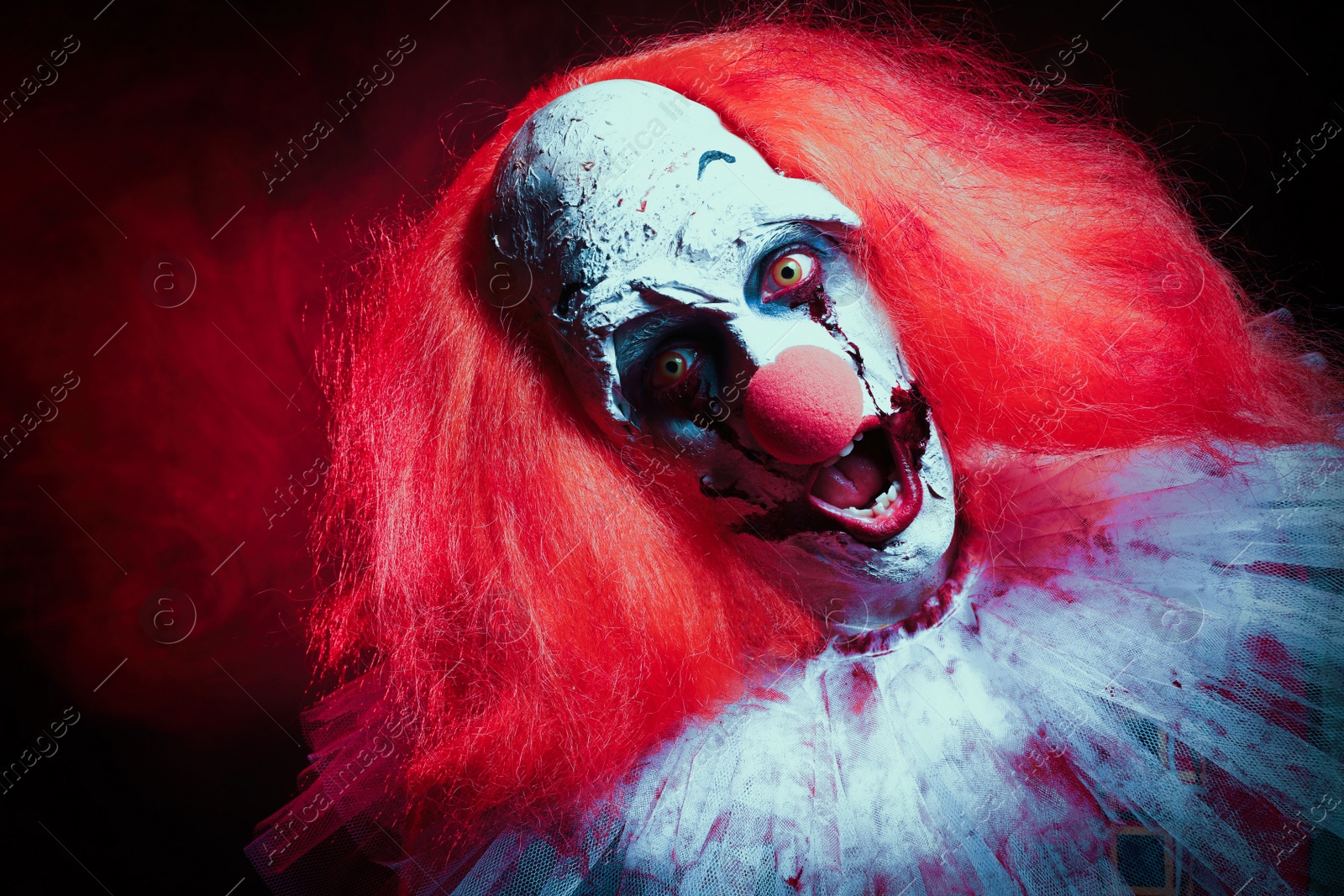 Photo of Terrifying clown on dark background. Halloween party costume