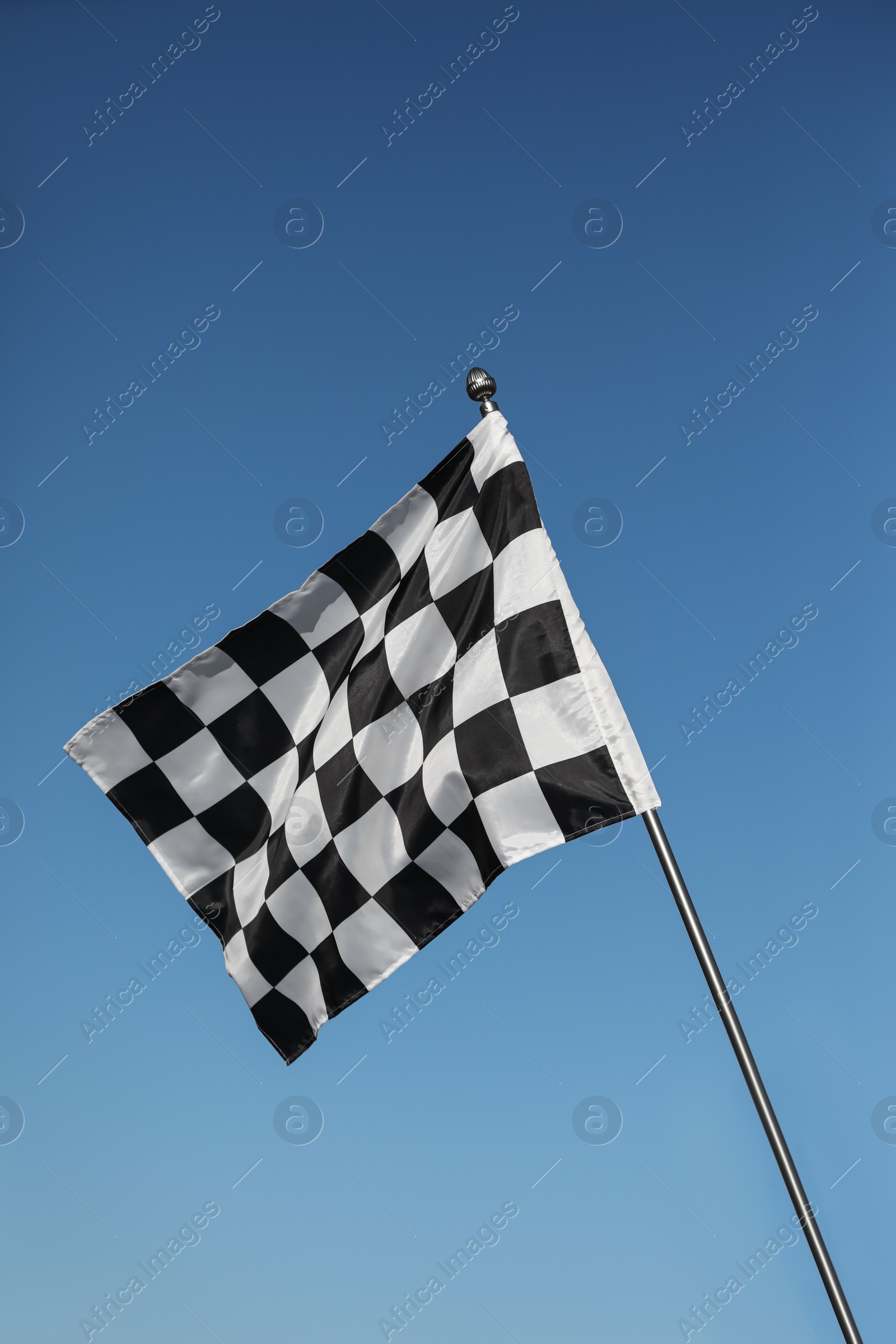 Photo of Woman holding checkered finish flag on light blue background, closeup