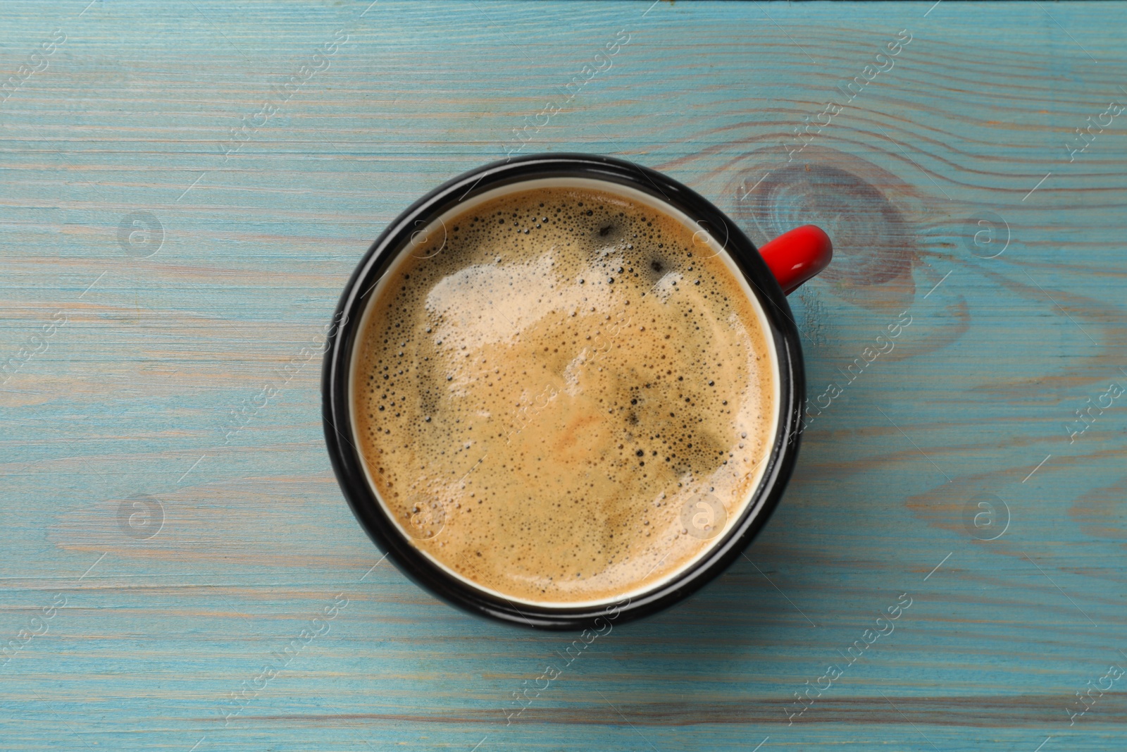 Photo of Cup of aromatic coffee on light blue wooden table, top view