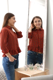 Young beautiful woman looking in mirror indoors