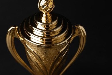 Photo of Golden trophy cup on black background, closeup