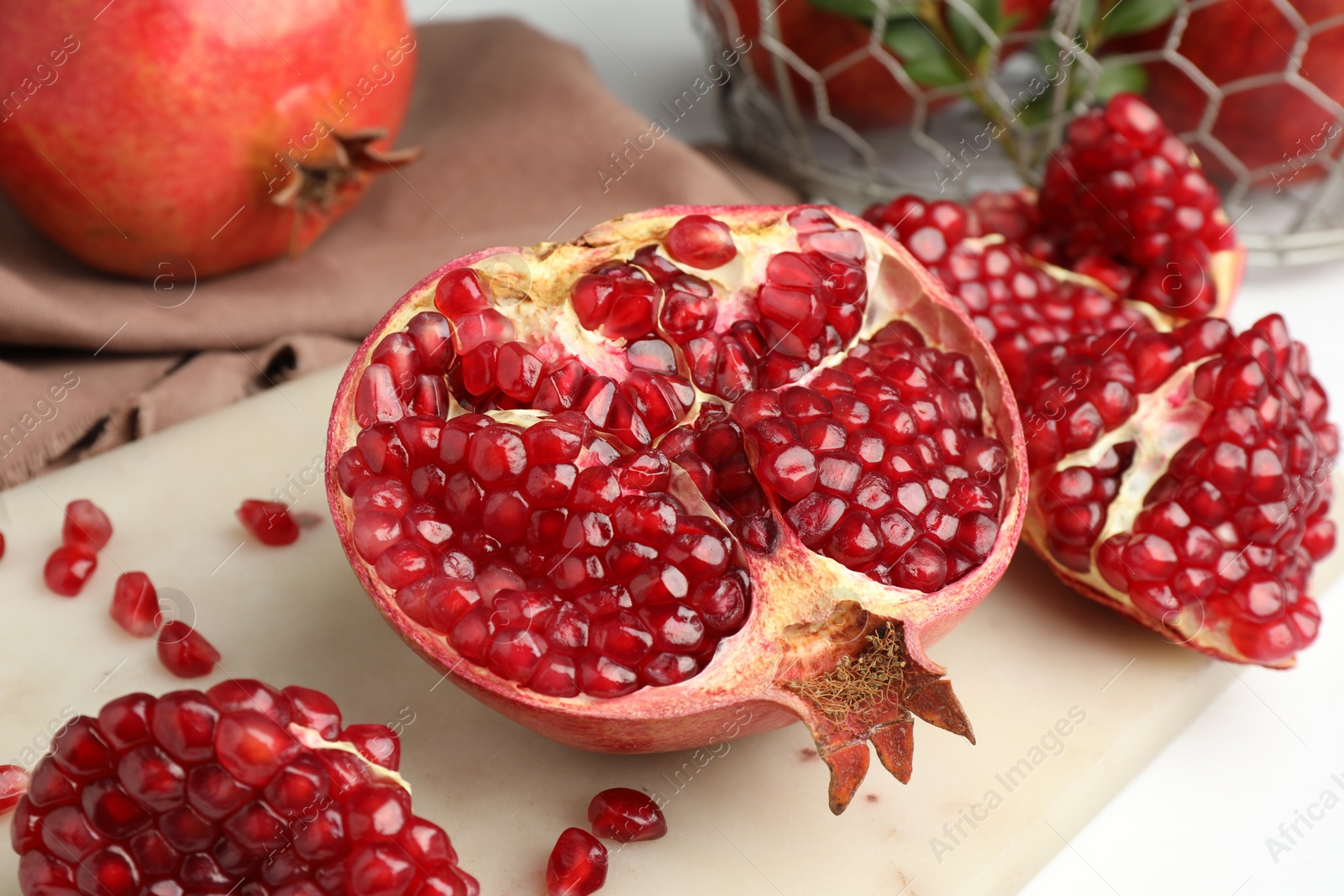 Photo of Piece of fresh pomegranate and seeds on white table, closeup