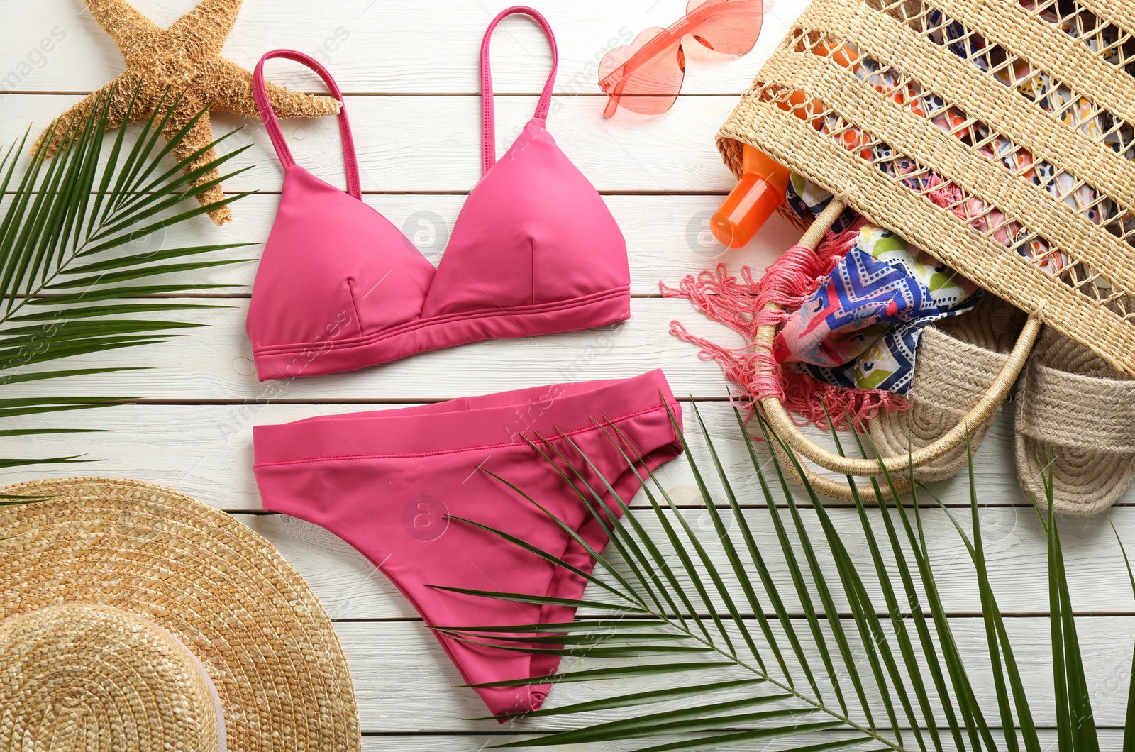 Photo of Beautiful pink bikini and beach accessories on white wooden background, flat lay