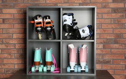 Pairs of roller skates on shelves near brick wall