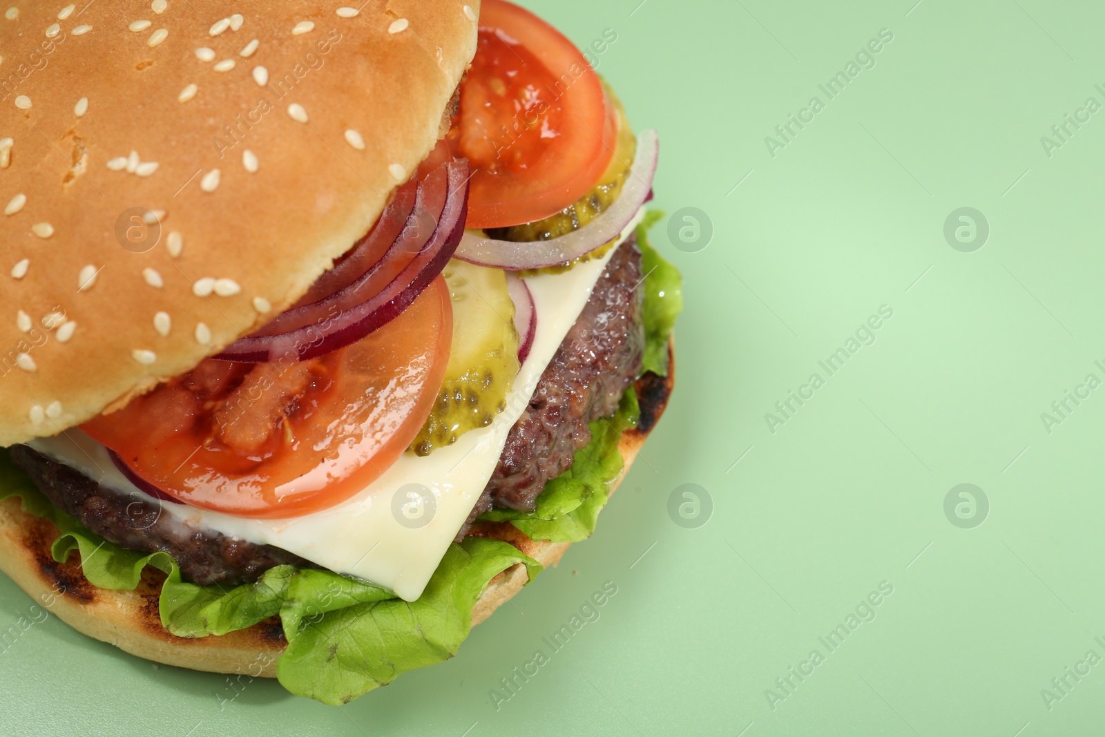 Photo of Burger with delicious patty on green background, closeup. Space for text