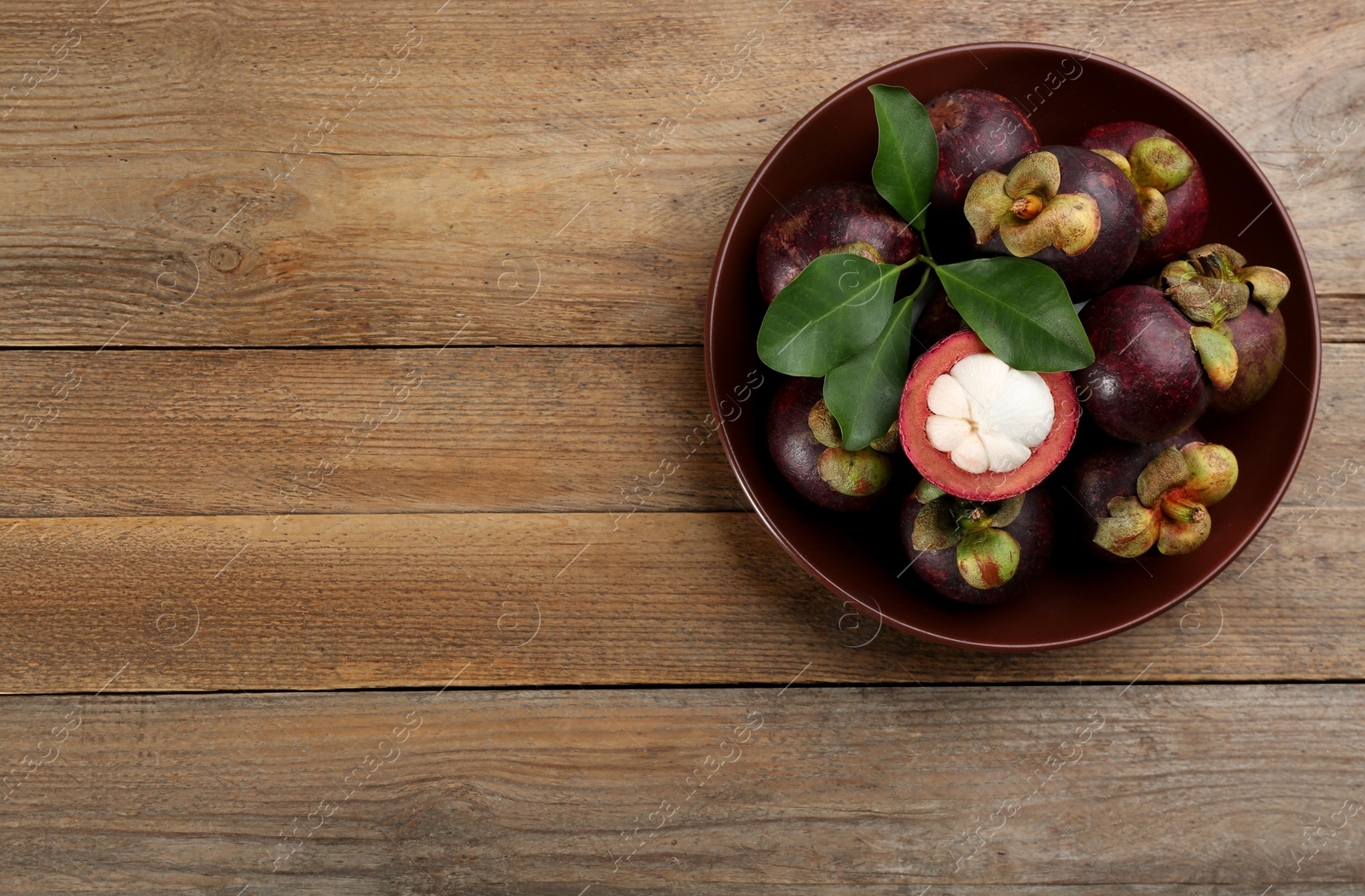 Photo of Delicious tropical mangosteens on wooden table, top view. Space for text
