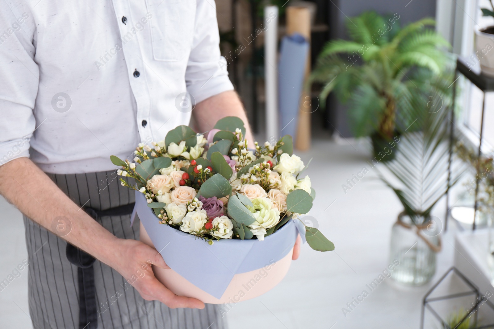 Photo of Male florist holding box with flowers at workplace