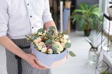 Photo of Male florist holding box with flowers at workplace