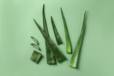 Cut aloe vera plant on light green background, flat lay