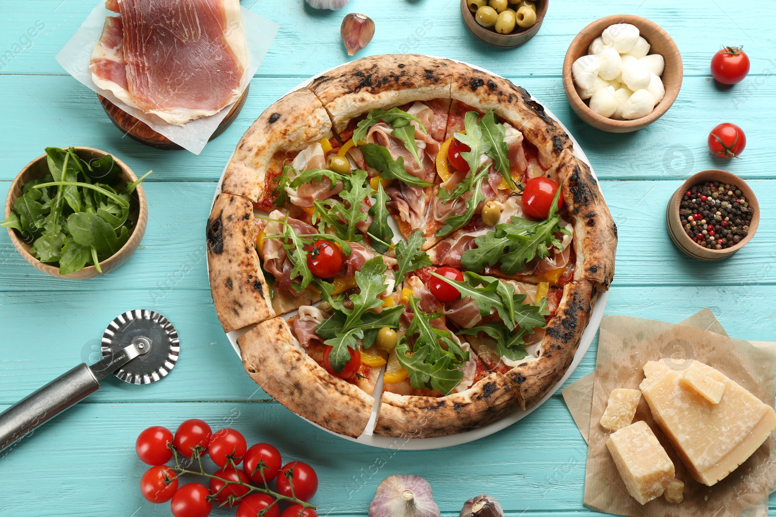 Photo of Tasty pizza with meat and arugula on light blue wooden table, flat lay