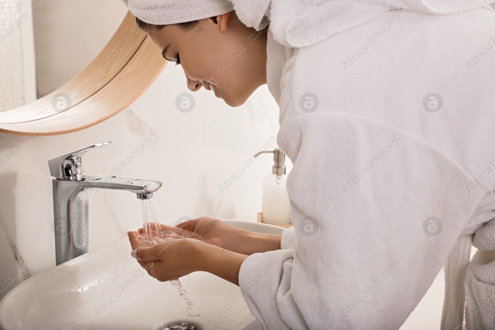 Photo of Beautiful teenage girl washing face with cleansing foam in bathroom. Skin care cosmetic