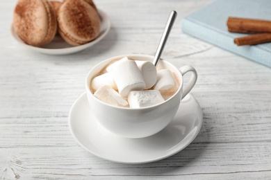 Photo of Tasty cocoa drink with marshmallows in cup on wooden table