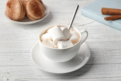 Tasty cocoa drink with marshmallows in cup on wooden table