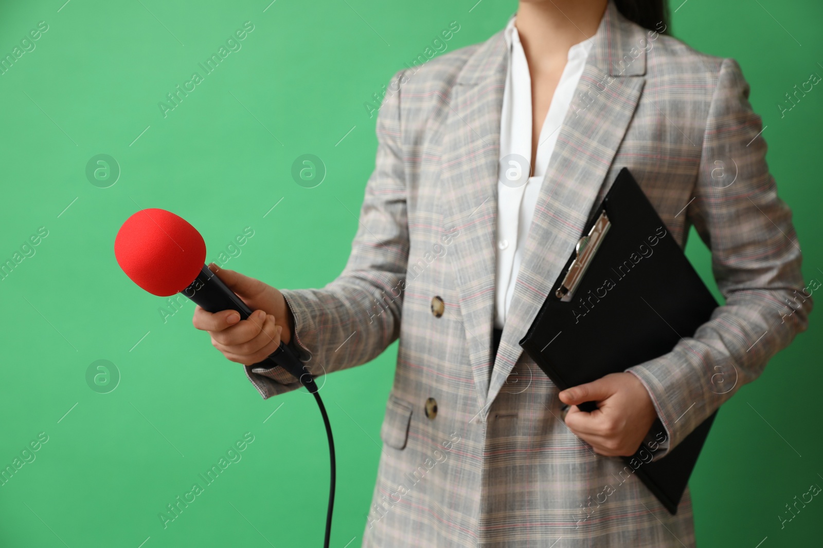 Photo of Journalist with microphone and clipboard on green background, closeup