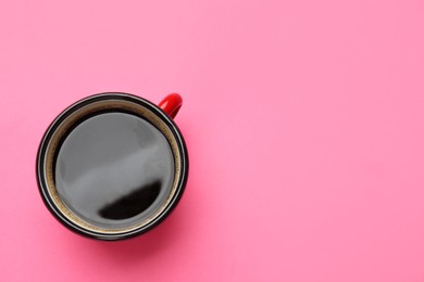 Photo of Fresh coffee in cup on pink background, top view. Space for text