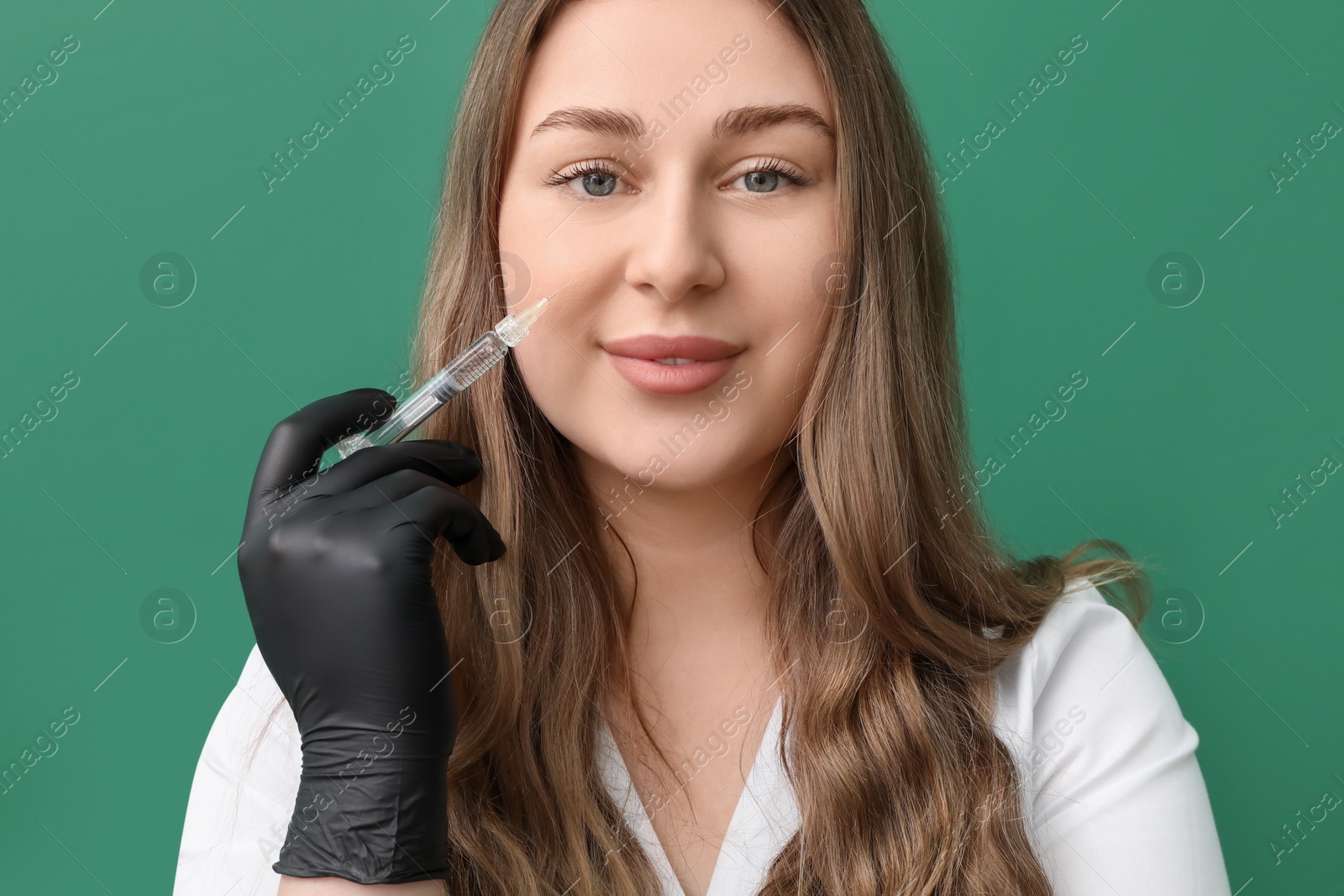 Photo of Cosmetologist with syringe on green background, closeup