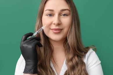 Cosmetologist with syringe on green background, closeup