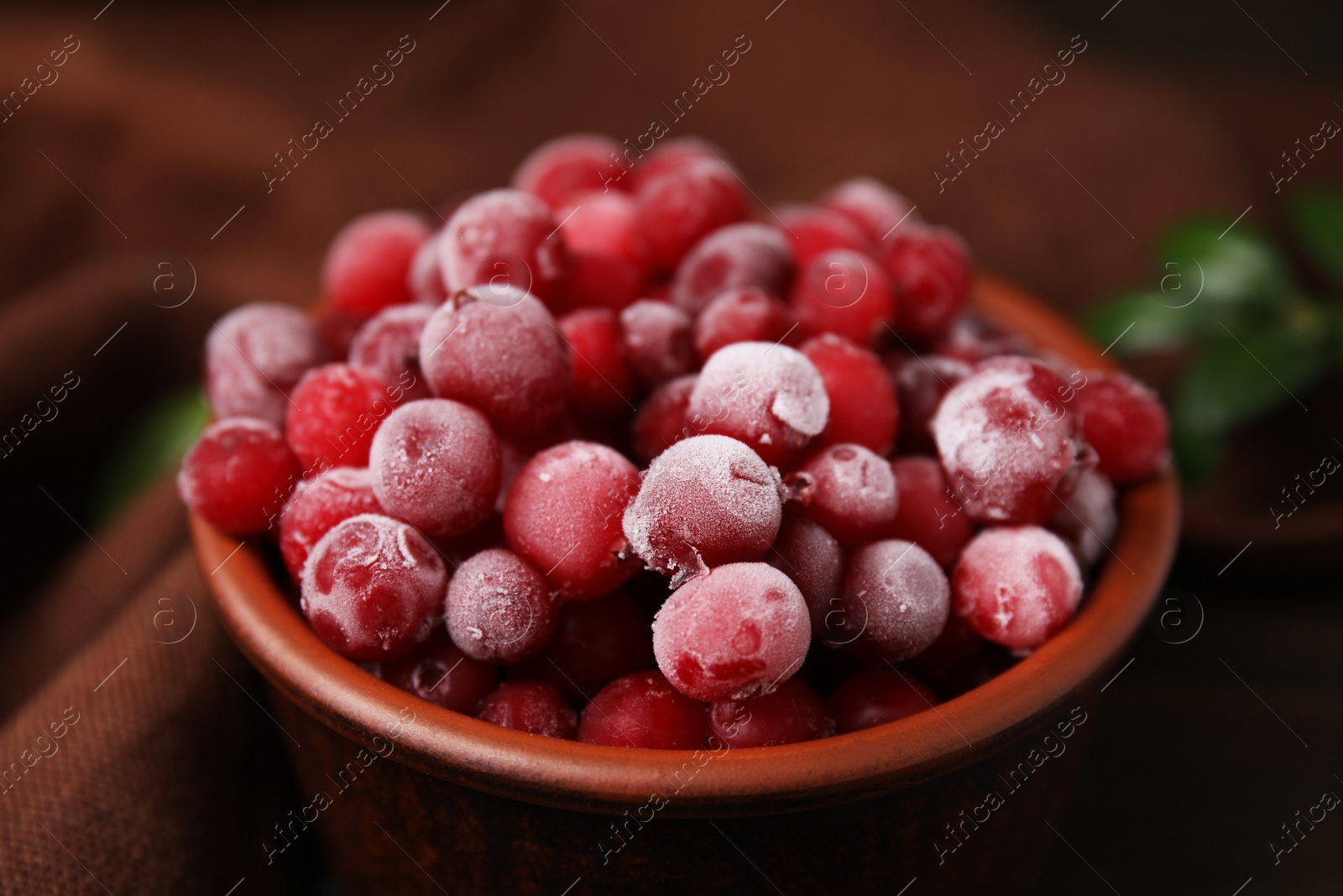 Photo of Frozen red cranberries in bowl on table, closeup