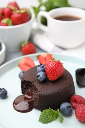 Delicious chocolate fondant, berries and mint on plate, closeup