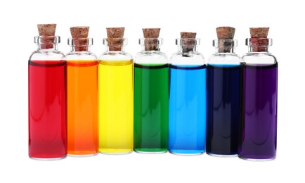 Glass bottles with different food coloring on white background