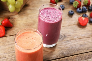 Photo of Glasses with different tasty smoothies and ingredients on wooden table, closeup