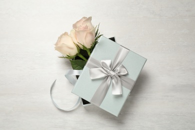 Photo of Elegant gift box with beautiful flowers on white table, top view