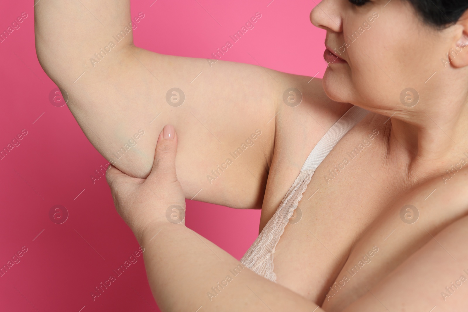Photo of Obese woman with flabby arm on pink background, closeup. Weight loss surgery