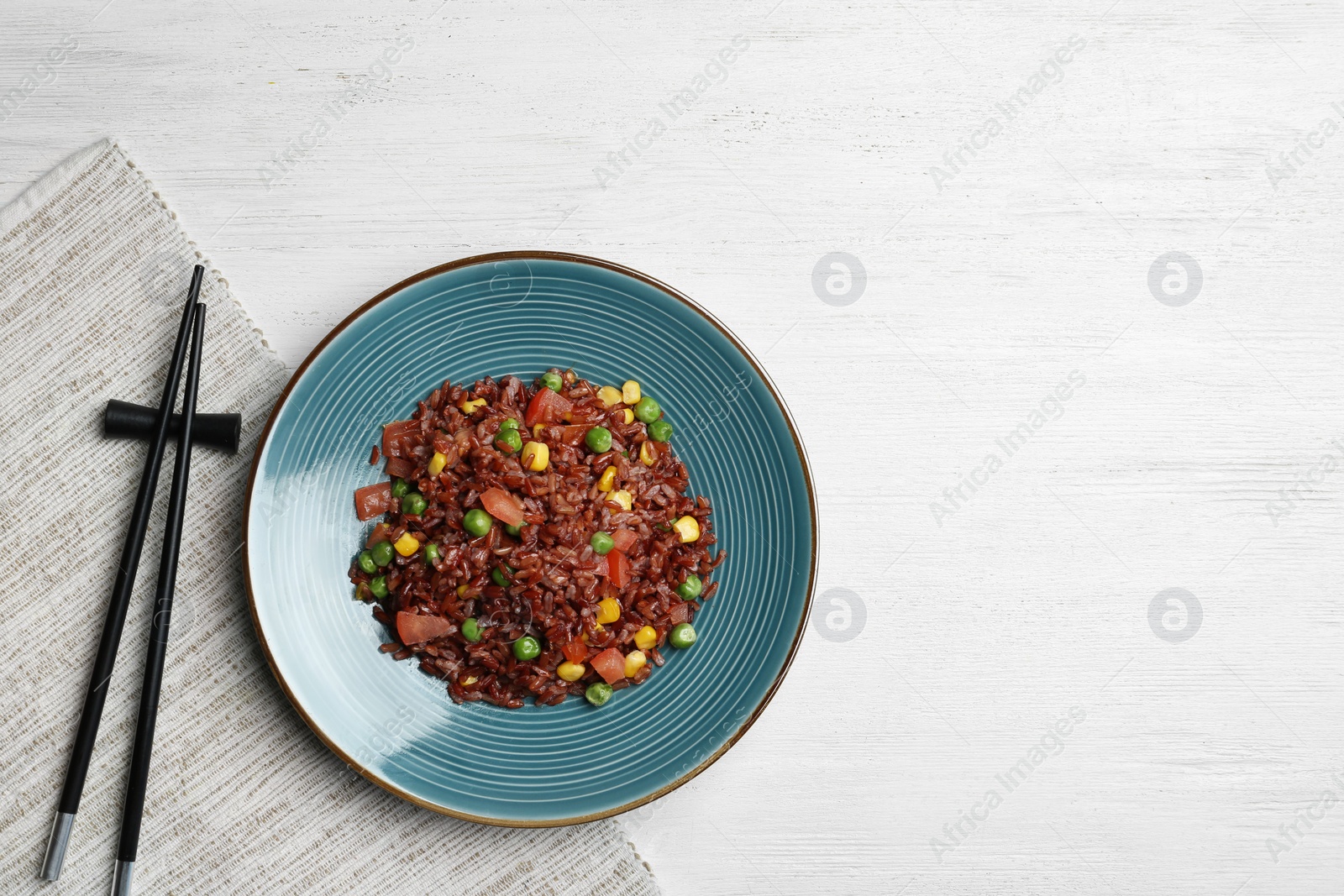 Photo of Plate of boiled brown rice with vegetables served on table, top view. Space for text