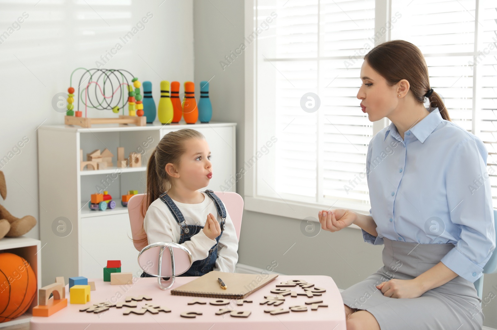 Photo of Speech therapist working with little girl in office