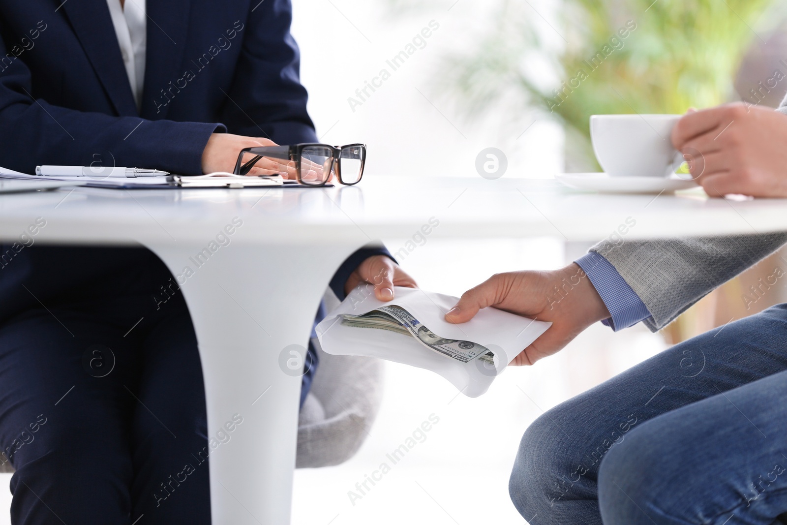Photo of Man giving bribe to woman under table in office, closeup
