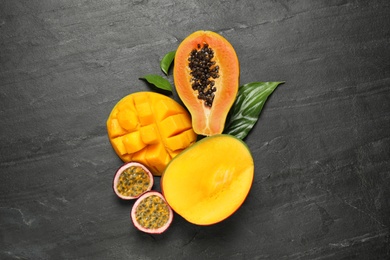 Photo of Fresh ripe papaya and other fruits on black table, flat lay