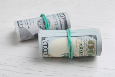 Photo of Rolled dollar banknotes on white wooden table, closeup. American national currency