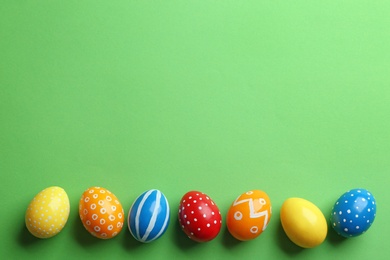 Flat lay composition of painted Easter eggs on color background, space for text